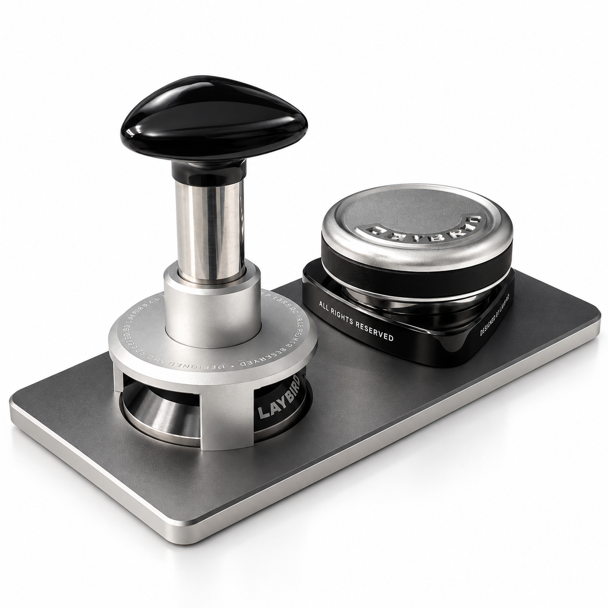 Three-quarter view of a TriPress tamper and TriSpin distributor resting on a rectangular MagHub tool base.