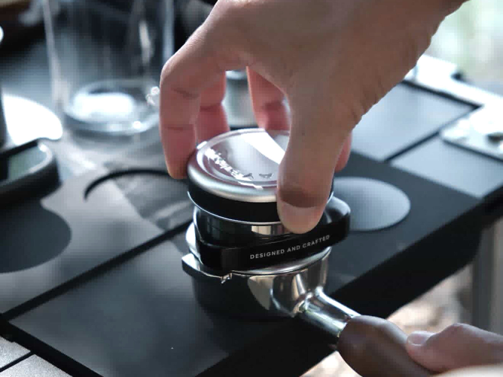 Hand rotating the LAYBIRD TriSpin coffee distributor on a portafilter before tamping